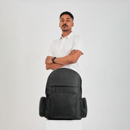 A man standing behind a black backpack