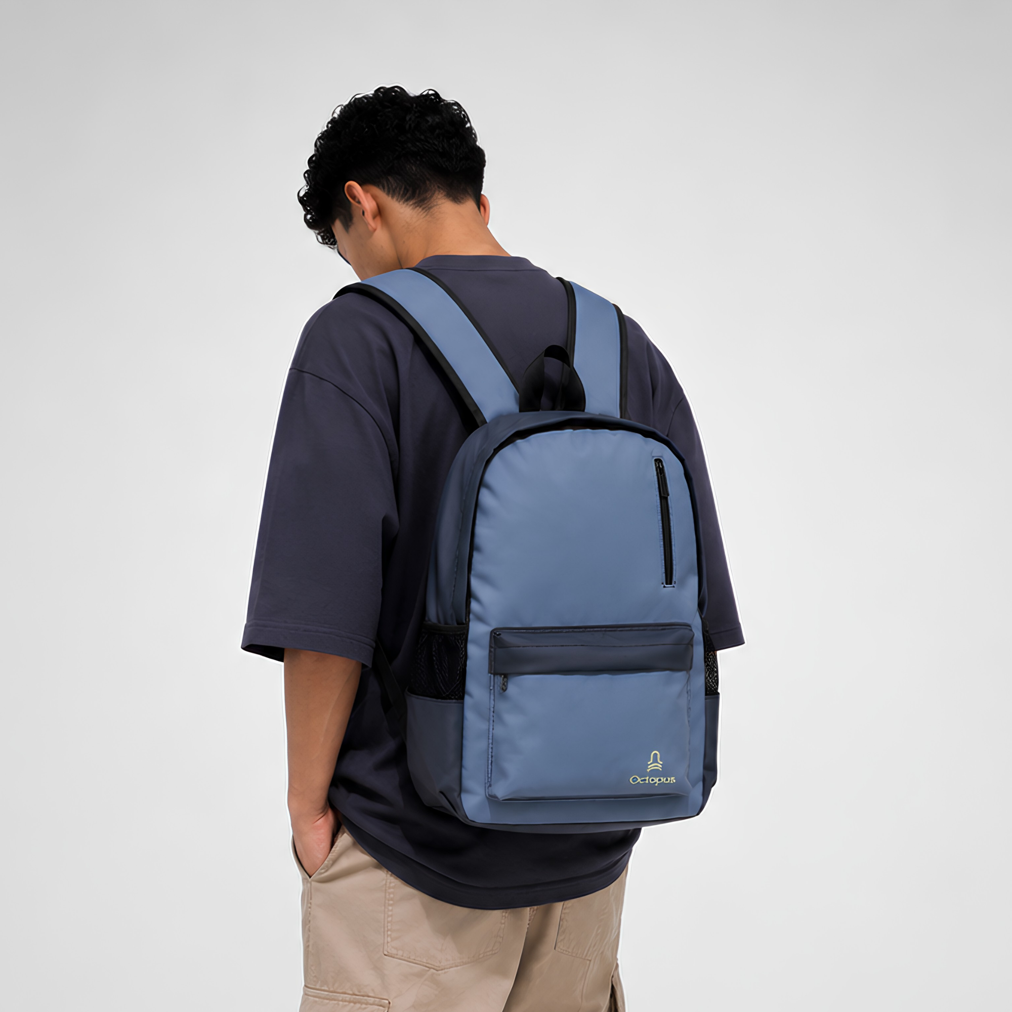 a young man wearing a blue laptop backpack with a yellow octopus logo on the front pocket