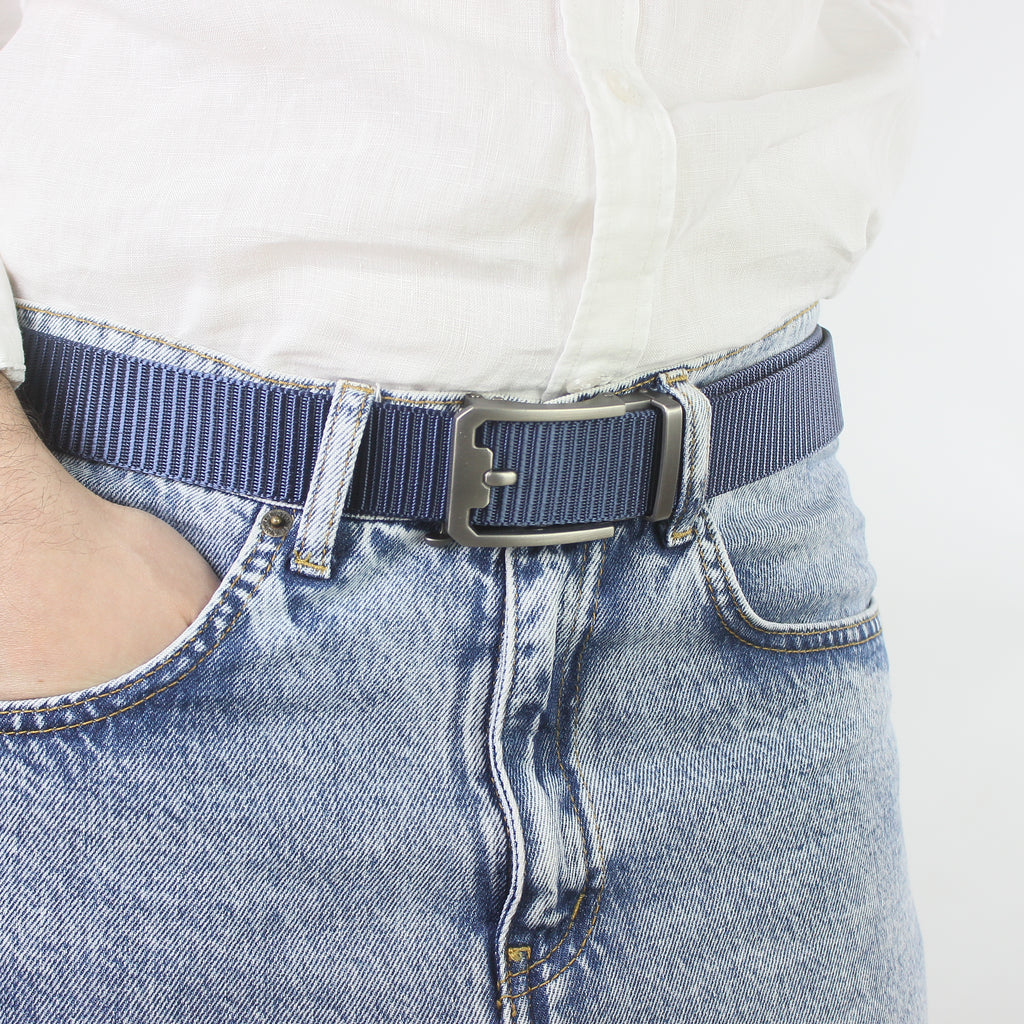 Close-up of a man wearing a navy blue textured nylon belt with light wash denim jeans and a white linen shirt